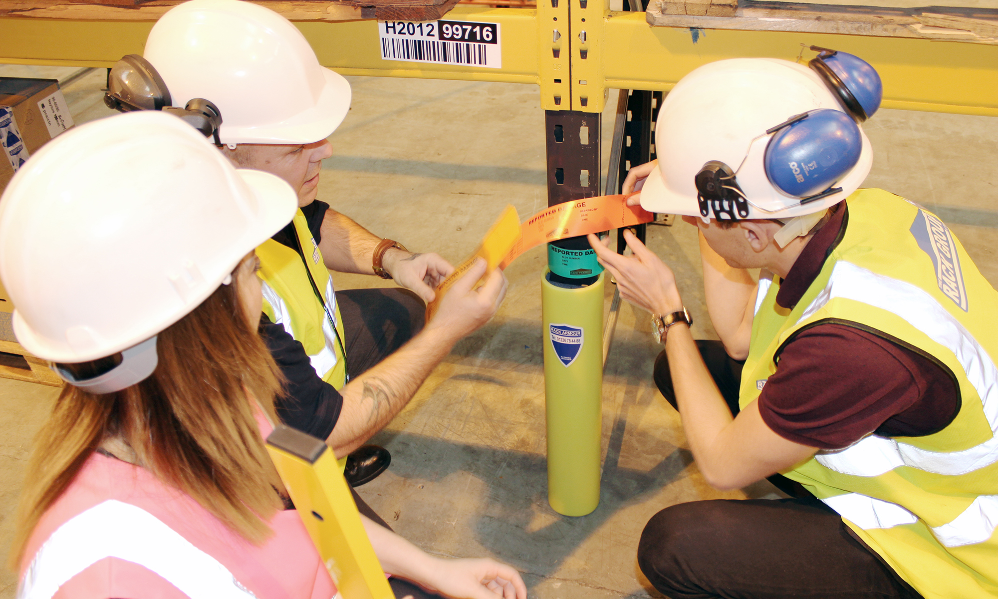 Warehouse safety training session with team applying rack damage labels to upright protector